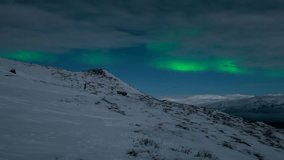 Time lapse woman watching northern lights on a mountain with clouds moving in opposite directions - Powered by Shutterstock - Get 15% off with code: PIKWIZARD15