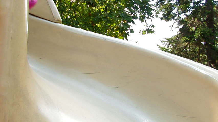 A young girl slides down a sliding board.  Set of two clips.