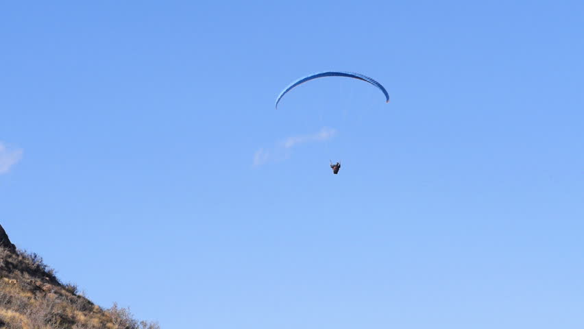 A paraglider descends behind a hill for landing. HD 1080p