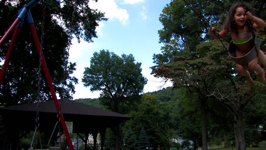 A young girl swings on a swing set.