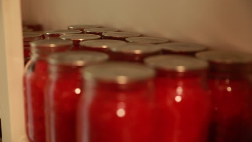 Food canned in mason jars on shelves in a storage room in a house