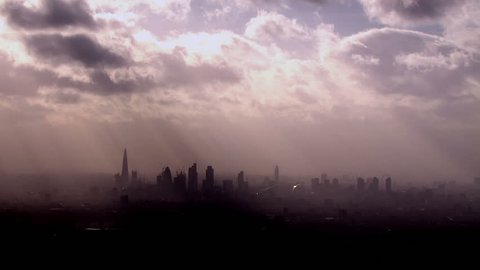 Dramatic aerial view of the London skyline on a hazy autumn morning with rays of light beaming through the clouds above. Video Stok
