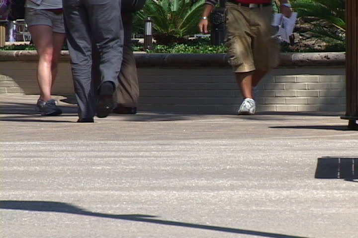 The feet and legs of shoppers and pedestrians are shown walking along the sidewalk in an outdoor mall. Royalty-Free Stock Footage #516796