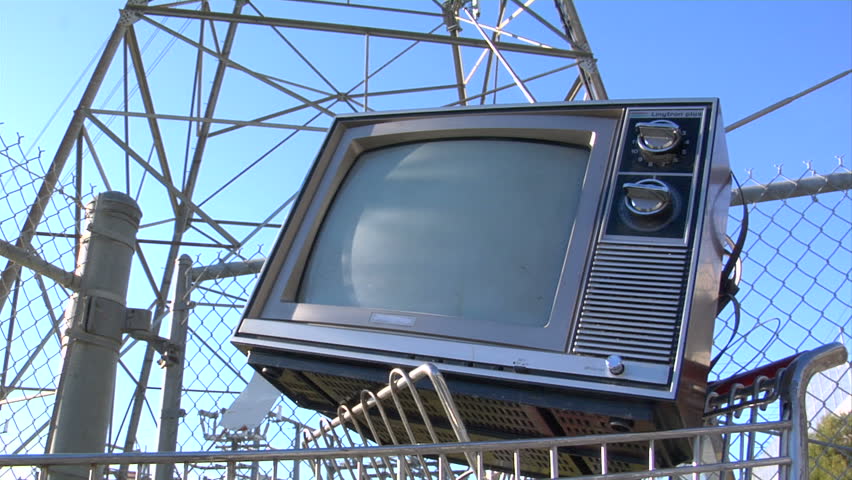This is a unique shot of a retro tv in a shopping cart in front of a power
