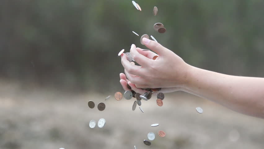 Coins falling and overflowing a woman's hands. Slow-motion, 40% real time.
