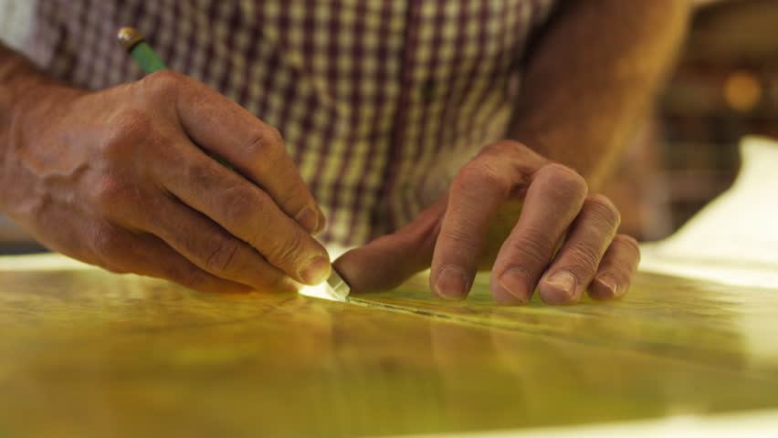 Closeup of fingers and glass cutter scoring glass