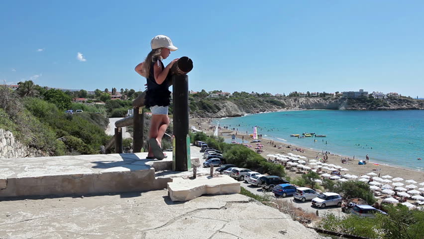 Small child a girl standing on observation deck in Coral Bay beach and looking at Mediterranean seacost, Paphos, Cyprus