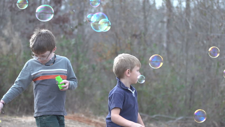 Children playing with bubbles outside, slow motion, 40% real time. brothers,