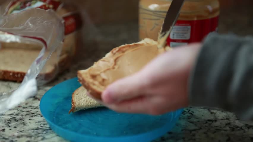 A man prepares a peanut butter sandwich in his home
