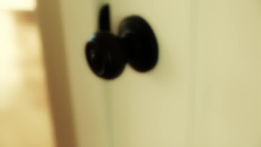 A hand twisting a door knob and opening a door