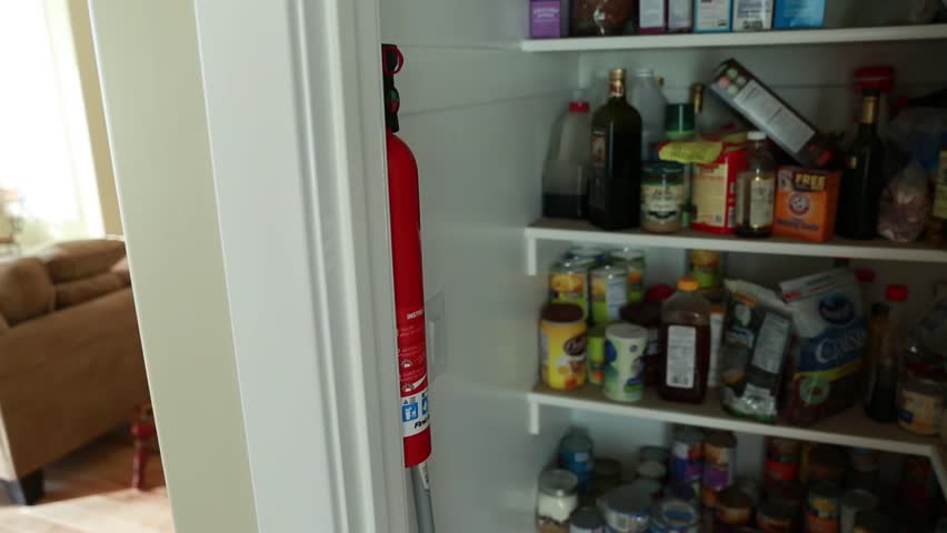 A man removes a fire extinguisher from the pantry and then puts in back