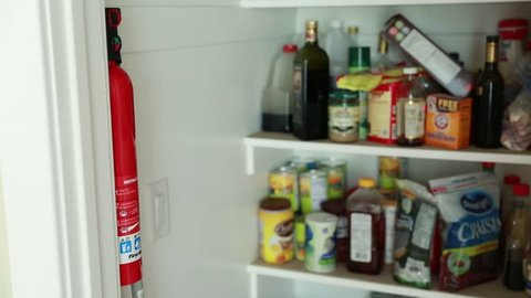 A man uses a fire extinguisher that he gets from the pantry