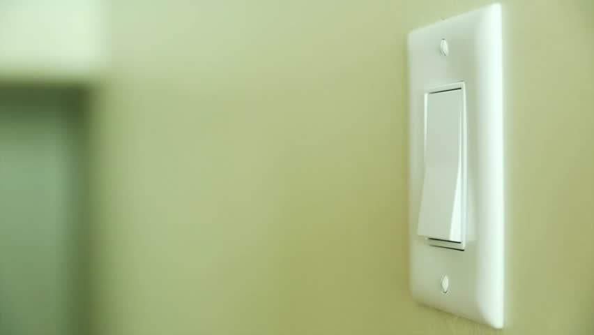 A hand turning on and off a light switch in a house