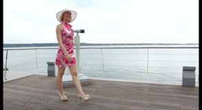 Attractive female tourist in red dress walking and looking around. Steadicam shot in high definition.