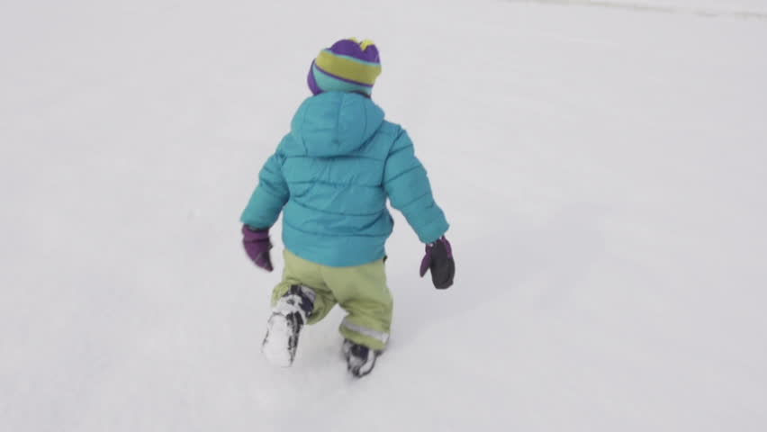 Slow Motion Rear View Of A Cute Little Boy Running Over Snow Covered Field On A