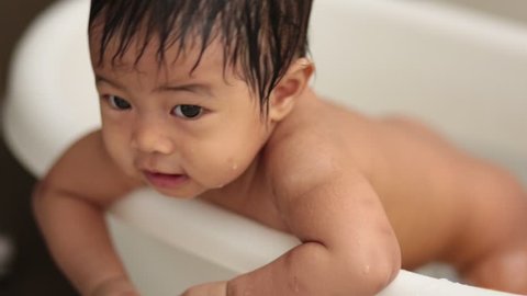 adorable Asian baby having bath in white tub