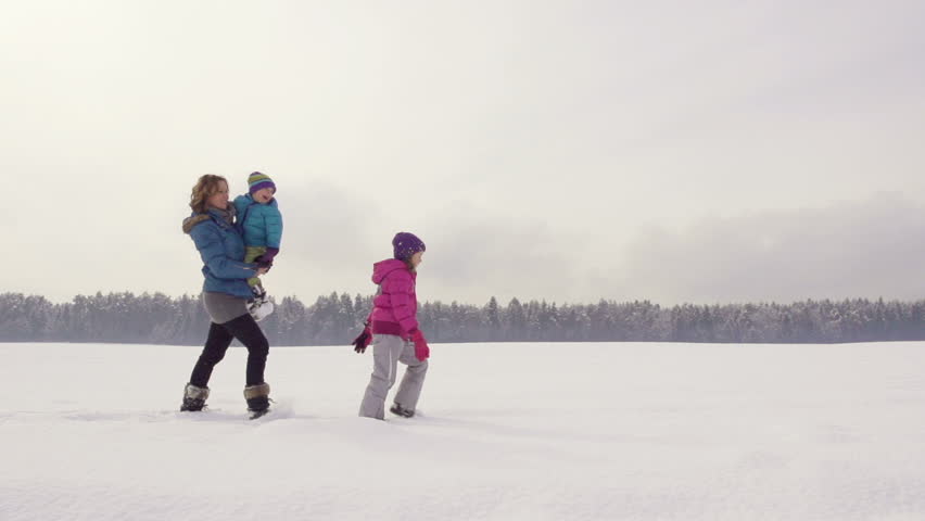 Beautiful Slow Motion Of Mother, Daughter And Son Hiking Over Snow Covered