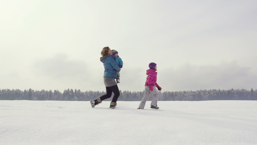 Beautiful Slow Motion Of Mother, Daughter And Son Running Across Snow Covered