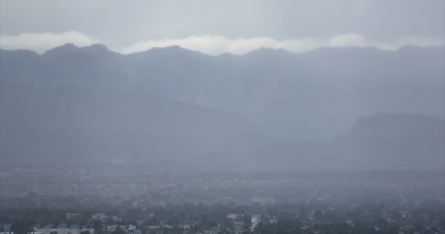 Time lapse of clouds and fog clearing over a city next to a mountain.  4K Ultra