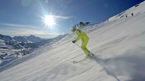 side view alpine skier skiing short swings on ski slope on sunny winter day in Austrian mountains