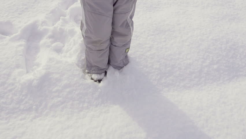 Slow Motion Of Child's Legs Walking Through High Fresh Snow On A Winter Day.