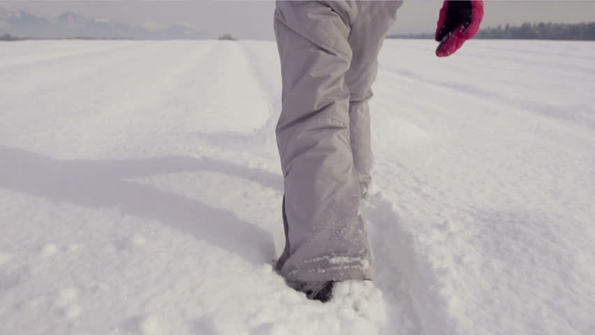 Slow Motion Rear View Of A Girl's Legs Kicking Snow Outdoors On A Sunny Winter