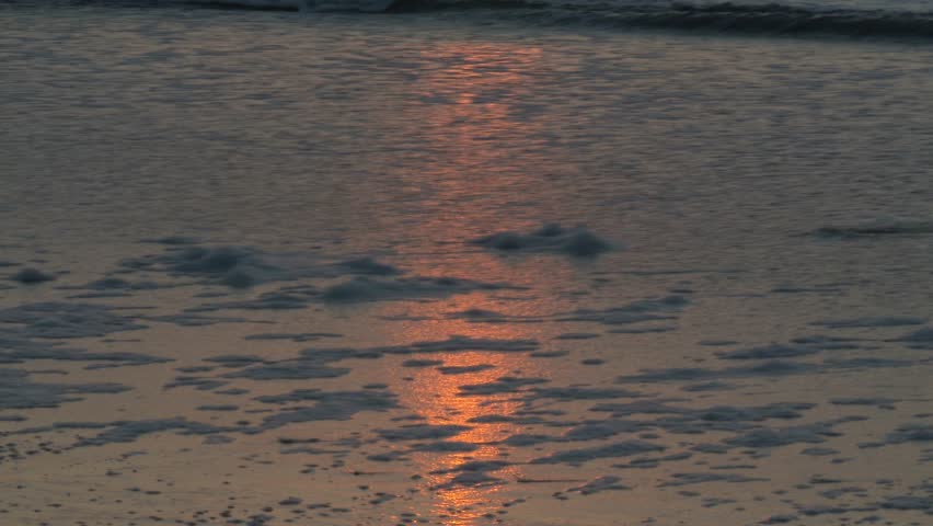 The rising sun reflects in the surf.  In 4K UltraHD.