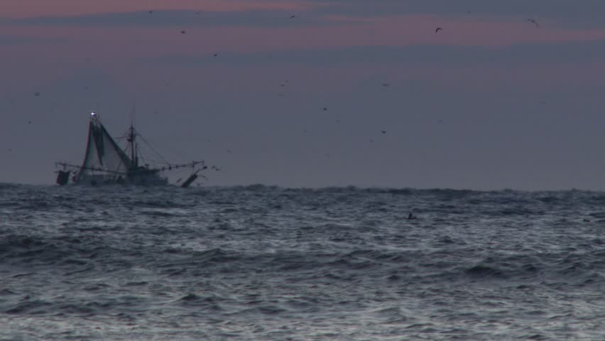 A commercial fishing boat on the morning horizon in the distance.  In 4K