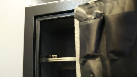 A man takes a pistol from a metal gun safe in his house