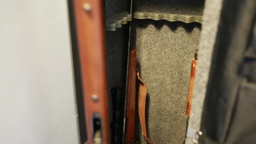 A man removes guns from a metal gun safe in his house