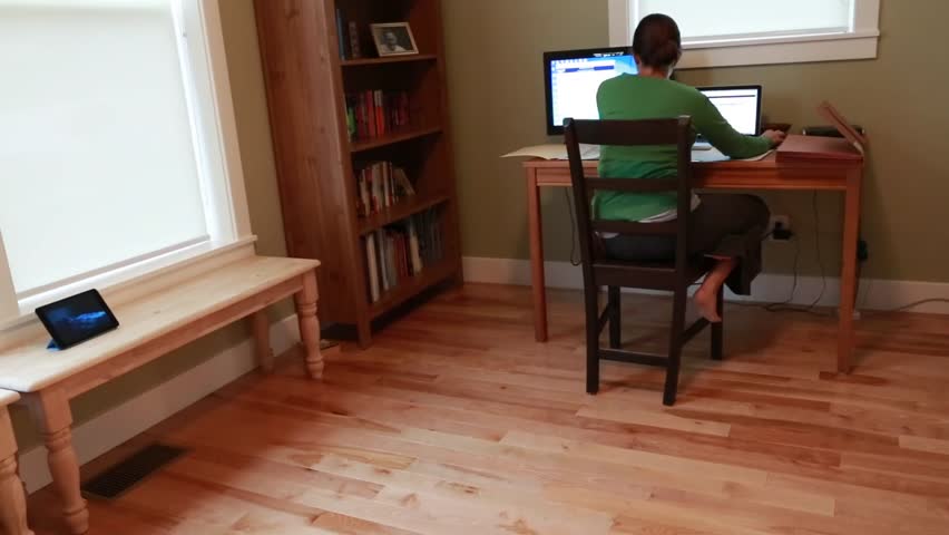 A working mother in a home office while her toddler plays in a monster outfit