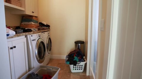 A father does the laundry while his toddler boy plays beside him