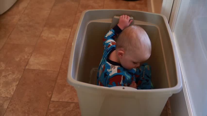 A boy playing in a laundry basket in his house