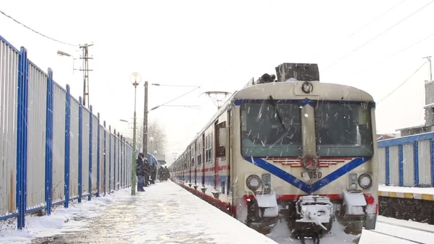 Train running through snow covered station. Electric train approaches camera