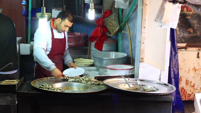 ISTANBUL - JAN 2: Man cooks and sells deep fried anchovies in a small restaurant