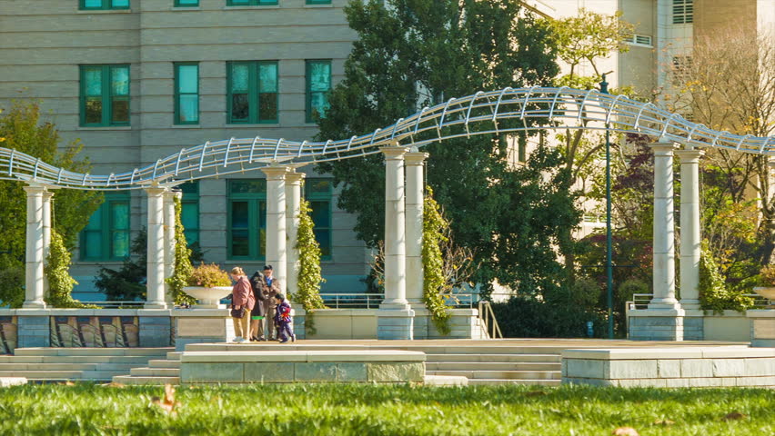 Tourists Visiting and Enjoying Pack Square Park in Downtown Asheville, North Carolina on a Sunny Autumn Morning with Fall Colored Trees and Green Grass.