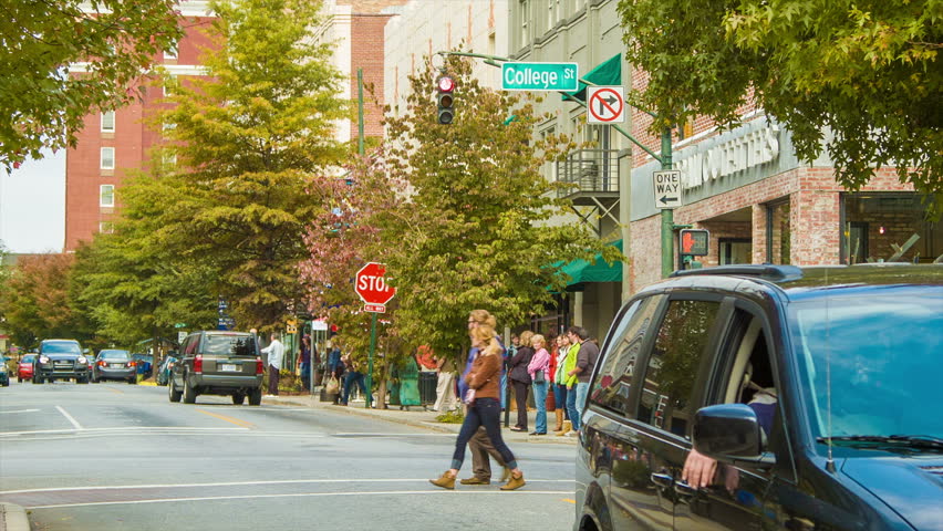 Pedestrian and Vehicular Traffic on College Street in Downtown Asheville, NC with Autumn Colored Trees on a Sunny Day.