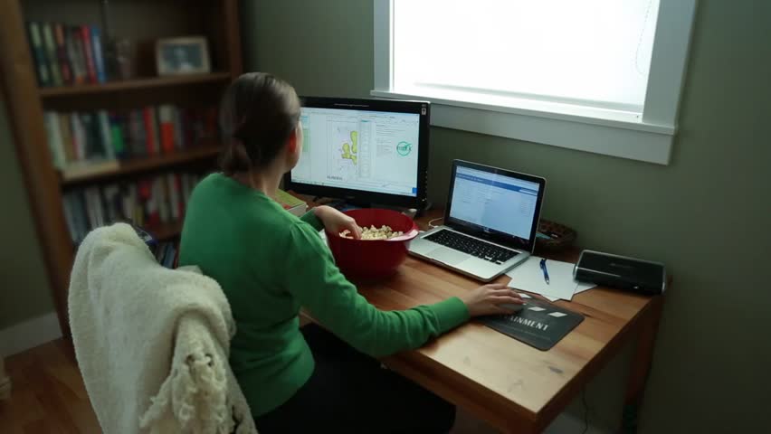 A woman working in her home office while snacking on popcorn