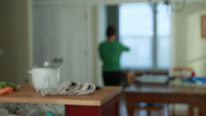 A woman walking through her house while snacking on popcorn