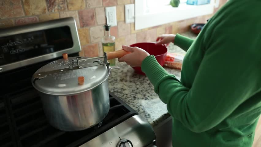A woman making popcorn in her home for a snack