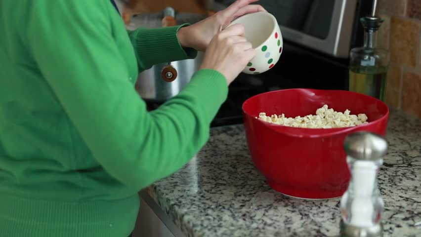 A woman making popcorn in her home kitchen