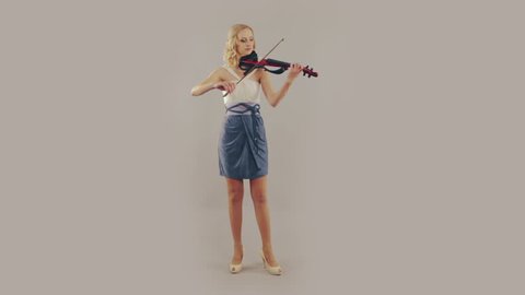 Young woman playing the violin on gray background