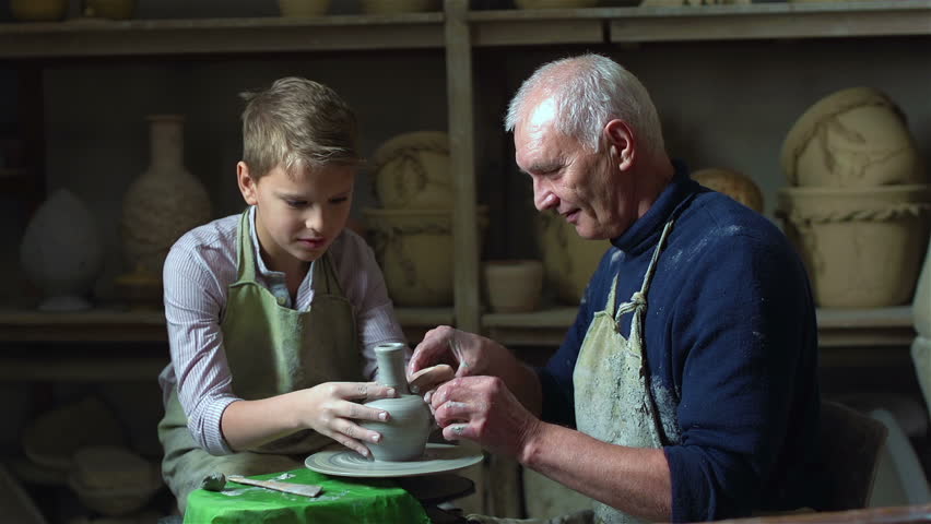 Elderly artisan sharing experience with his teen student