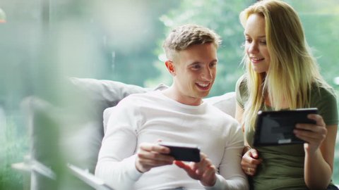 Attractive young couple with technology relaxing together at home