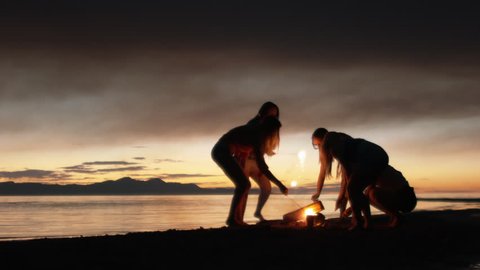 Group of Five Teenage Girls Lighting Sparklers At A Campfire On The Beach At Dusk Stock Video