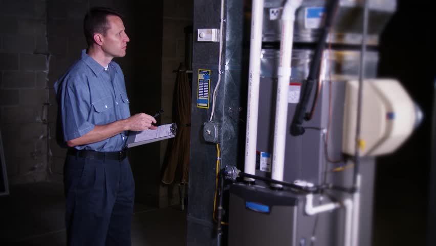 A furnace serviceman inspects a household furnace.