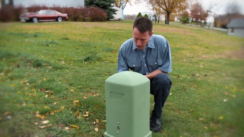 A utility worker inspects an exterior utility outlet.