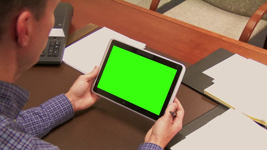 A finance officer works at his desk with a tablet PC. Green screen tablet for