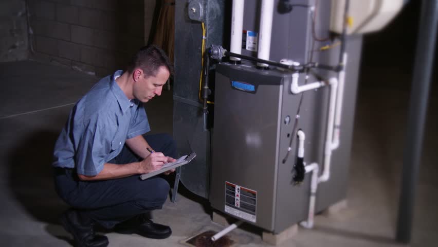A furnace serviceman inspects a household furnace.