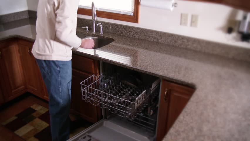 A man puts dishes into his dishwasher.